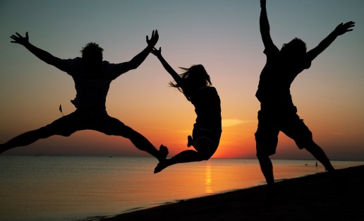 FriendsJumpingOnBeachInSunset